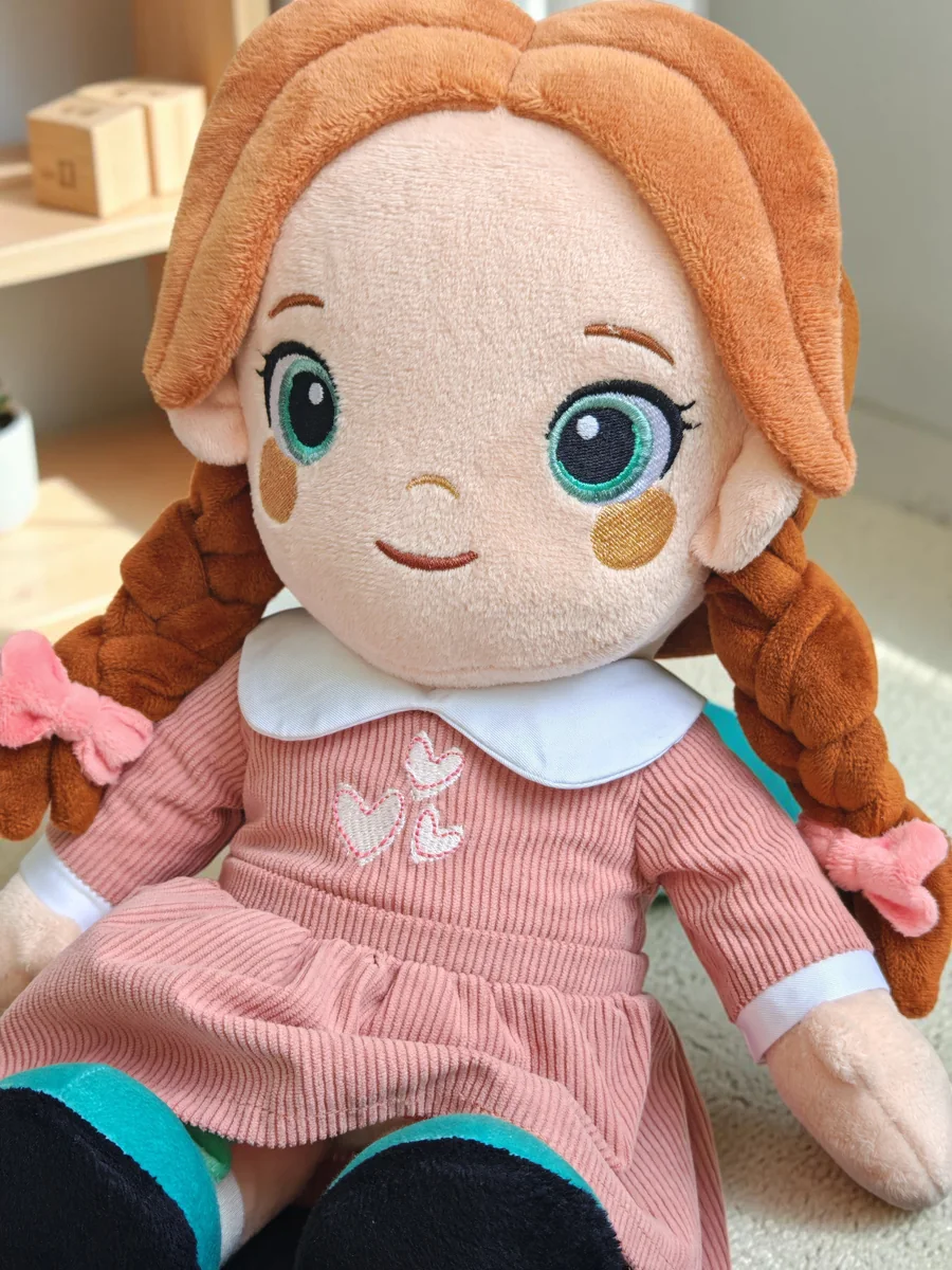 Lotti, a Playnitive baba közelről: gesztenyebarna copfok, hímzett szemek és rózsaszín kordruha